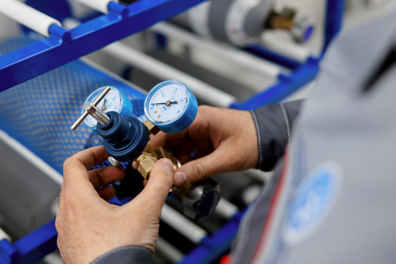 Illustrative photo: adjusting a pressure gauge on a regulator.